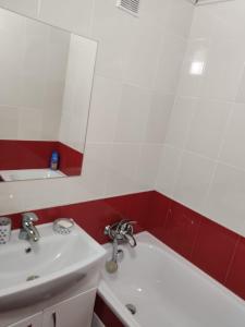 La salle de bains est pourvue d'un lavabo, d'un miroir et d'une baignoire. dans l'établissement Затишна квартира, à Tcherkassy