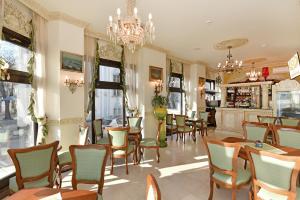 a restaurant with tables and chairs and a chandelier at Royal Hotel in Varna City