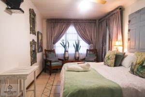 1 dormitorio con 2 camas, sillas y ventana en Snooze-A-Lot Guesthouse, en Secunda