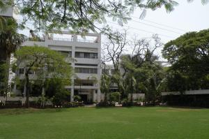 a large white building with a green lawn in front of it at Nasiklub in Nashik