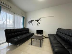 sala de estar con sofá de cuero negro y mesa en EX Itoman Apartment 302 en Itoman