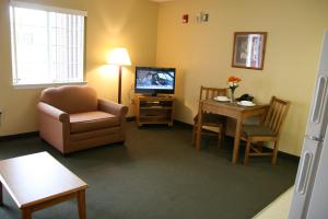 ein Wohnzimmer mit einem TV, einem Stuhl und einem Tisch in der Unterkunft Affordable Suites Wilson in Wilson