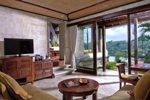 sala de estar con TV y ventana grande en The Royal Pita Maha, en Ubud