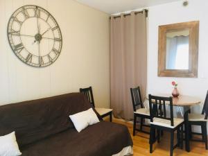 Una sala de estar con un sofá y un reloj en la pared. en La grande Ourse de Font Romeu, en Font-Romeu