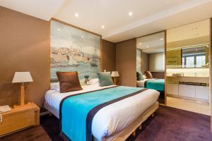 a bedroom with a large bed with a painting on the wall at Hôtel Hélios in Juan-les-Pins