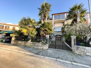 budynek z palmami przed płotem w obiekcie Villa Palma Rovinj w Rovinj