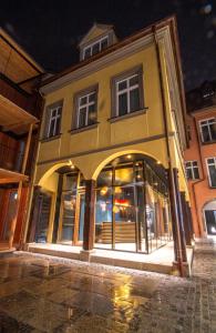 ein gelbes Gebäude mit Fenstern auf einer Straße in der Nacht in der Unterkunft Le Baldinger Boutique Hotel in Bamberg