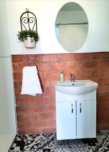 a bathroom with a white sink and a brick wall at Anna's Place in Jeffreys Bay