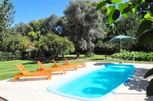 a swimming pool with chairs and an umbrella at Los Olivos Loft in Rosario