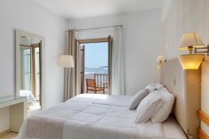 una camera con un grande letto bianco e un balcone di Lithos by Spyros & Flora ad Agios Ioannis