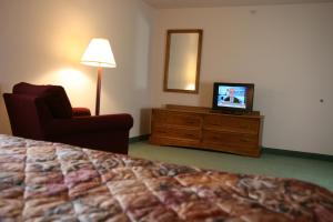 a hotel room with a bed and a chair and a television at Affordable Suites Rocky Mount in Rocky Mount