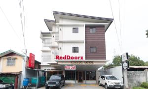 a red door coffee shop with cars parked in front of it at RedDoorz Plus @ Diola Villamonte Bacolod in Bacolod