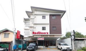 ein Café mit roter Tür, vor dem Autos geparkt sind in der Unterkunft RedDoorz Plus @ Diola Villamonte Bacolod in Bacolod City