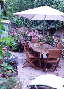 einen Holztisch mit Sonnenschirm in einem Garten in der Unterkunft B&B de charme La Maison des 5 Temps in Ferrette