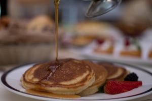 a pancake being drizzled with syrup on a plate with strawberries at InterContinental Taif, an IHG Hotel in Taif