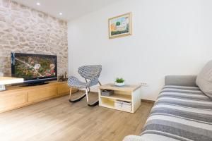 a living room with a couch and a tv at Dvori Stipanovi with heated pool in Donje Rašćane