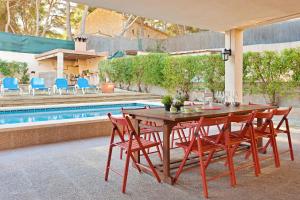 a wooden table and chairs next to a swimming pool at Villa Arenas in El Arenal