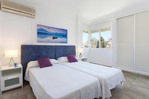 Un dormitorio blanco con una cama grande con almohadas moradas. en Villa Arenas, en Playa de Palma