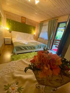 a bedroom with a bed and a vase of flowers on a table at Pensiunea Edy Turda in Turda