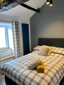 a bedroom with a bed with a yellow object on it at Bakers Cottage in Cockermouth