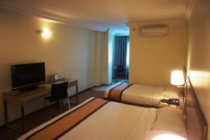 a hotel room with a bed and a desk with a television at Tyng Garden Hotel in Sandakan