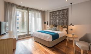 Schlafzimmer mit einem Bett, einem Schreibtisch und einem TV in der Unterkunft Gran View Apartments in Madrid