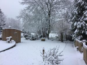 une cour recouverte de neige avec une clôture et des arbres dans l'établissement Les Crinieres En Brie, à Saint-Ouen-en-Brie