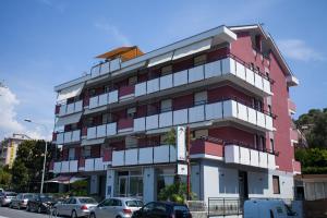 a red building with cars parked in front of it at Residence La Palma in Marina di Andora