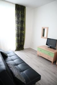 a living room with a black leather couch and a television at Hotel and Park Divoká Voda in Bratislava