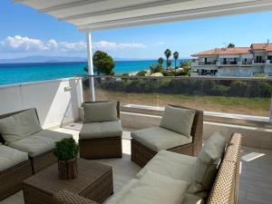 a patio with couches and chairs and a view of the ocean at Villa Theodora in front of the sea in Hanioti