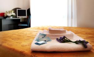 ベッラーリア・イジェア・マリーナにあるHotel Excelsiorの花の飾られたテーブルの上にタオルを積み重ねる