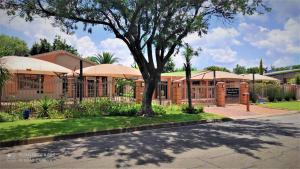un edificio con un albero di fronte di Premiere Guesthouse a Bloemfontein
