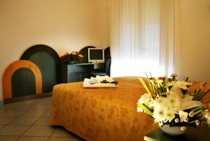 Zimmer mit einem Bett und einem Tisch mit Blumen in der Unterkunft Hotel Excelsior in Bellaria-Igea Marina