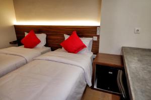 two beds with red pillows in a hotel room at Guest House 555 NKI in Duku