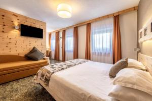 a bedroom with a large bed and a large window at Hotel Col di Lana in Canazei