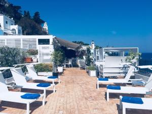 a patio with white chairs and the ocean in the background at Relais Maresca Luxury Small Hotel & Terrace Restaurant in Capri