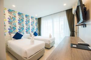 um quarto de hotel com duas camas e uma televisão de ecrã plano em Irin Beach Cha-am em Cha Am