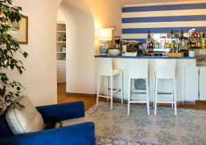 a living room with a bar with white stools at Relais Maresca Luxury Small Hotel & Terrace Restaurant in Capri