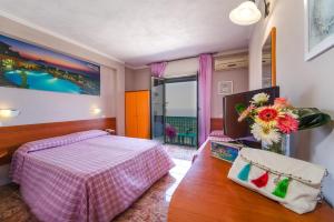 1 dormitorio con 1 cama y un jarrón de flores en Hotel Orizzonte Blu, en Tropea