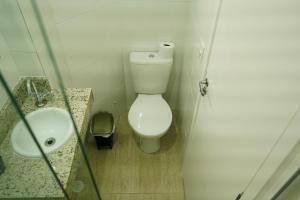 a small bathroom with a toilet and a sink at Enseada Village Guarujá in Guarujá