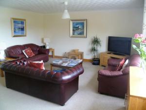 a living room with two leather couches and a television at Tigh na Sith in Lochinver
