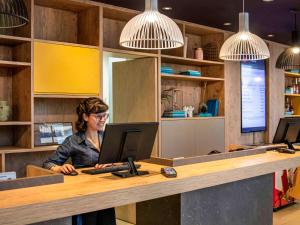 une femme assise sur un bureau avec un ordinateur portable dans l'établissement ibis Sao Paulo Tatuape, à São Paulo