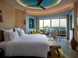 a bedroom with a large bed and a living room at Pullman Phu Quoc Beach Resort in Phu Quoc