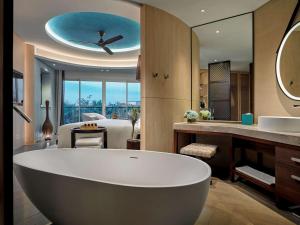 a bathroom with a large tub and a bedroom at Pullman Phu Quoc Beach Resort in Phú Quốc