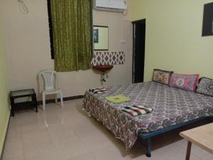 a bedroom with a bed and a table and a chair at Aguiar Guest House in Colva