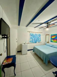 1 dormitorio con 1 cama y TV de pantalla plana en Suítes Astral, en Búzios