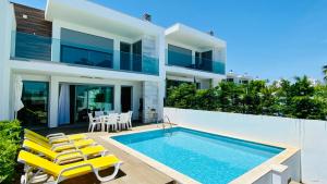 a villa with a swimming pool and yellow chairs at Albuhera by Check-in Portugal in Albufeira