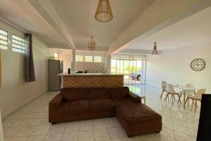 ein Wohnzimmer mit einem braunen Sofa und einer Küche in der Unterkunft Charmant appartement avec piscine in Le Robert