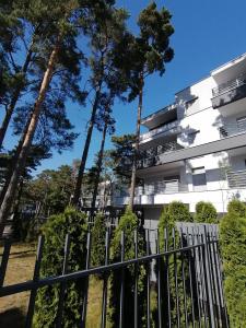 a fence in front of a building with trees at Apartment LILY - Baltic Park Pogorzelica in Pogorzelica