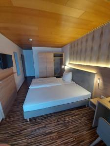 Schlafzimmer mit einem großen weißen Bett und einer Holzdecke in der Unterkunft Landgasthaus Hubertusklause in Bad Marienberg